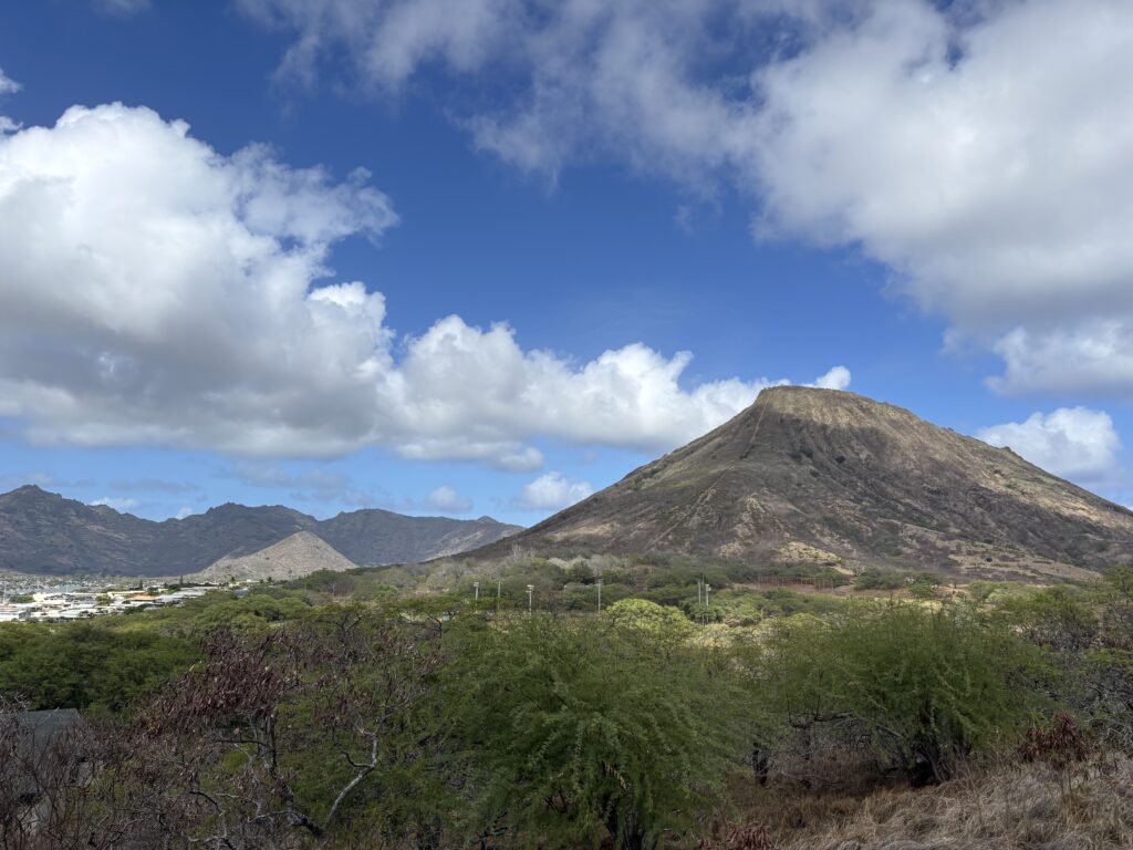 scenery with fluffy white clouds above a dormant volcano.